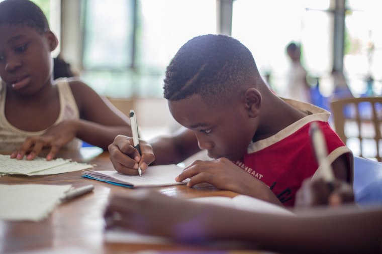 children working at a table, concentrating on their work