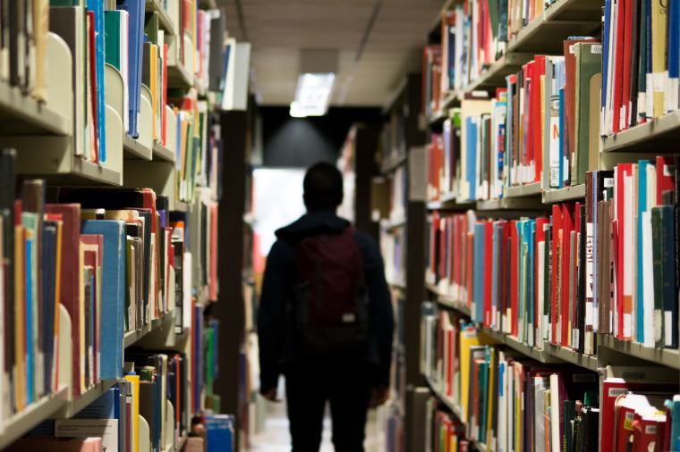 Student walking through two aisles of books